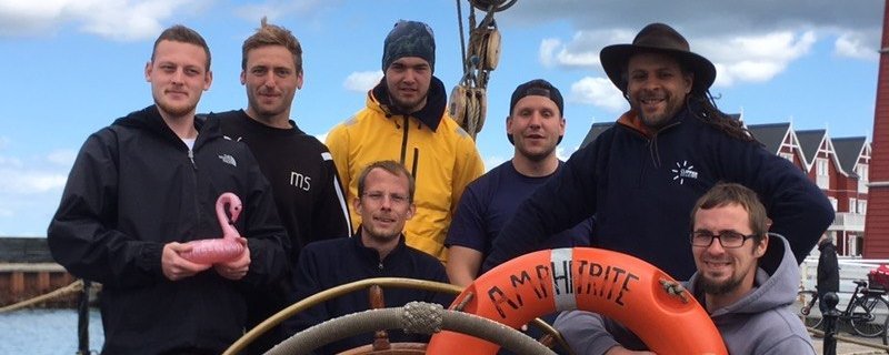 Gruppenfoto: Männer beim Segeln auf einem kleinen Schiff 