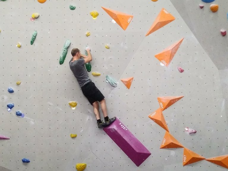 Sport: ein junger Mann beim Bouldern in der Halle