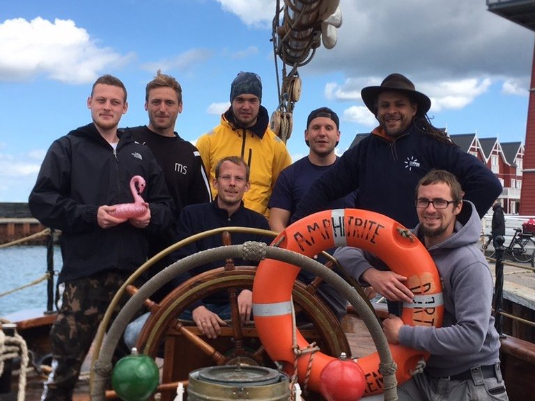 Gruppenfoto: Männer beim Segeln auf einem kleinen Schiff 