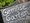 Eine Schieferplatte mit der weißen handschriftlichen Aufschrift „Gemüse Garten“ dient als Beschilderung neben einem Topf mit grünen Pflanzen.